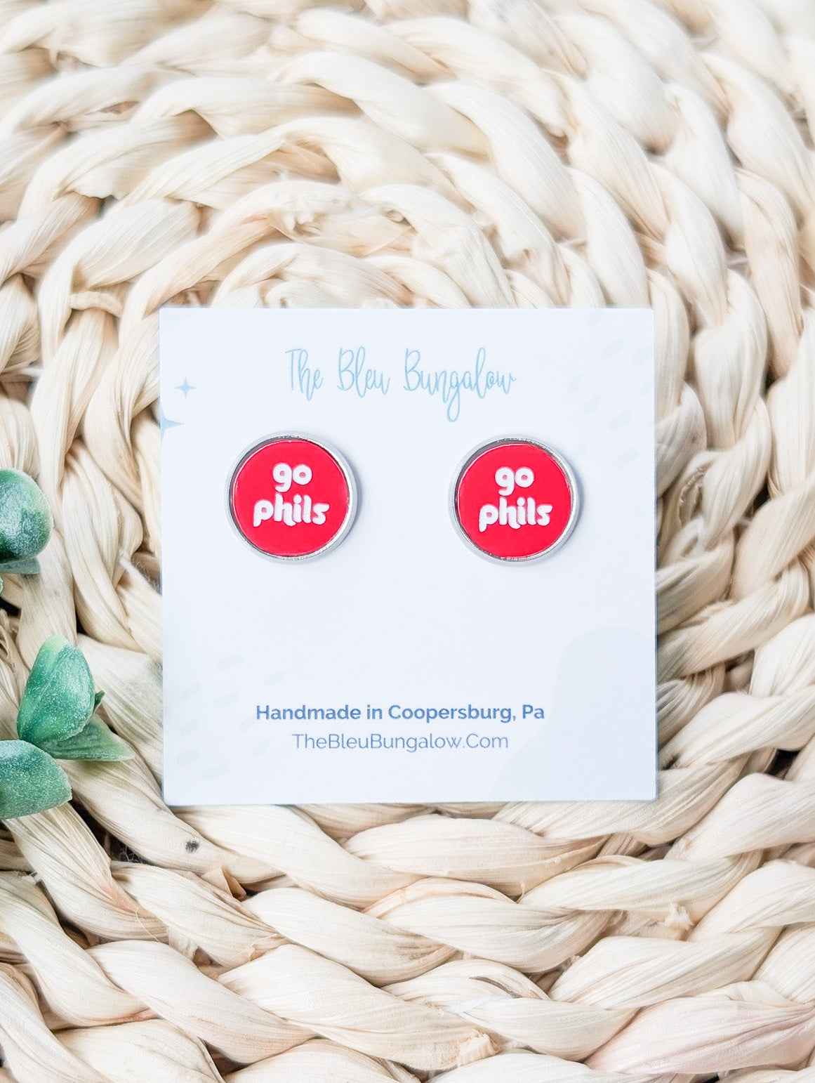 Pair of 'go pills?' earrings on a card with branding text, placed on a woven surface.